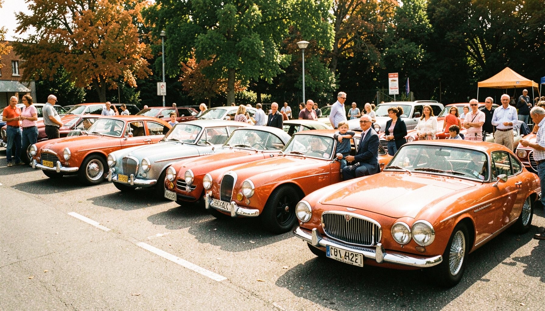 Mehrere Oldtimer-Rennwagen aufgereiht auf einem Parkplatz bei einer Wohltätigkeitsveranstaltung, Fahrer und Familienmitglieder stehen daneben